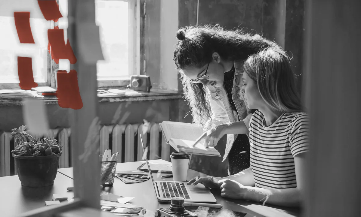 Two colleagues working through a problem together at a shared desk